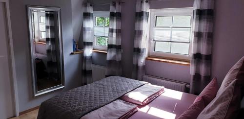 een kleine slaapkamer met een bed en 2 ramen bij Ferienwohnung Anna in Marienhafe