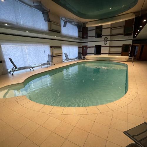 - une grande piscine dans un bâtiment avec 2 chaises dans l'établissement Domaine du Clos Pallacien, à Paillé