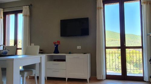 uma secretária branca com uma televisão numa parede com janelas em Delizioso appartamento a Capalbio con vista em Capalbio