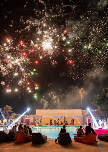a group of people sitting around a pool watching fireworks at BLACK AMBER BOUTIQUE HOTEL in Lampi