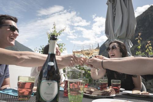 um grupo de pessoas sentadas à mesa com copos de vinho em Village Charme em Molini di Tures