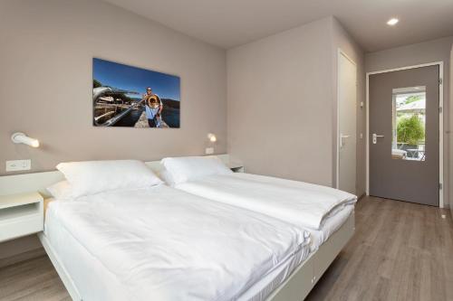 a white bedroom with a large bed and a painting on the wall at Jazz Hotel Ascona in Ascona