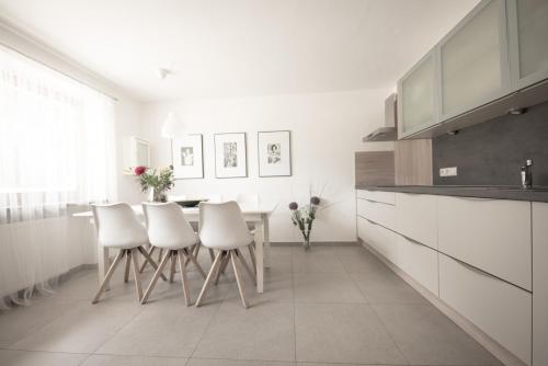 uma cozinha com armários brancos e uma mesa e cadeiras em Village Charme em Molini di Tures