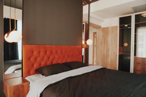 1 dormitorio con 1 cama grande y cabecero naranja en MERDZ Spa & Fitness Sky Apartment en Skopje