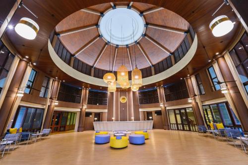 een grote kamer met een groot plafond met een tafel en stoelen bij The Tide Resort in Bangsaen