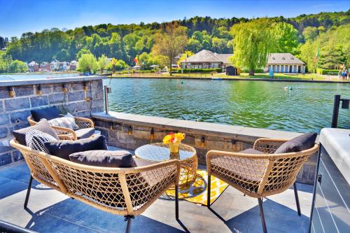 a patio with chairs and a table next to a body of water at Gatsby River I in Yvoir