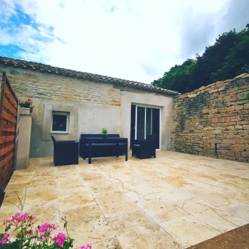 a patio outside of a building with a stone wall at Bienvenue chez Weiwei in Sancé