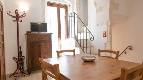 comedor con mesa de madera y TV en Casa Colombo & Casa Scipione by Rentbeat, en Ostuni