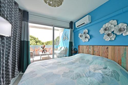 1 dormitorio con 1 cama con pared azul en T3 de 45 m2 avec terrasse - Entièrement climatisé - 2 chambres - 400m de la plage - résidence avec piscine, en Le Grau-du-Roi