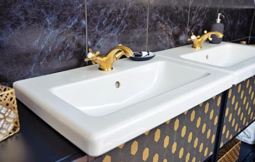 a bathroom with a white sink and gold faucets at Gatsby River II in Yvoir