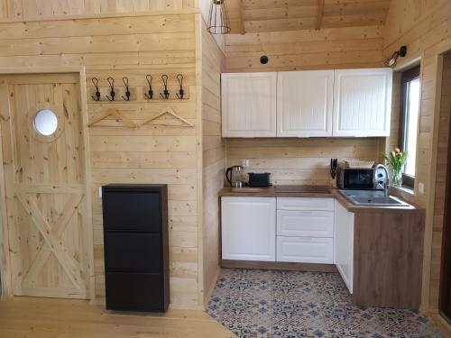 a kitchen with white cabinets and a black refrigerator at Domki przy jeziorze z prywatną plażą w Borach Tucholskich Pensjonat Alicja wczasy z dziećmi nowe luksusowe domki na skraju jeziora i lasu in Ostrowite