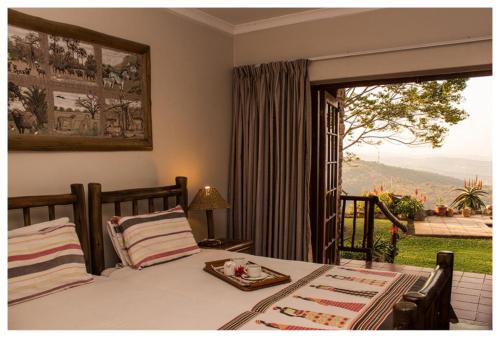 a bedroom with a bed and a window with a view at Leopards and Louries Bush Lodge in Camperdown