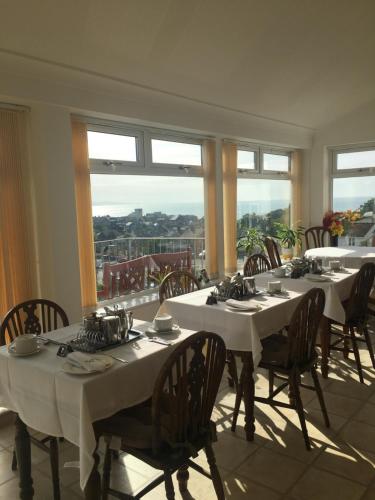 uma sala de jantar com mesas, cadeiras e janelas em Lucerne B&B em Lyme Regis