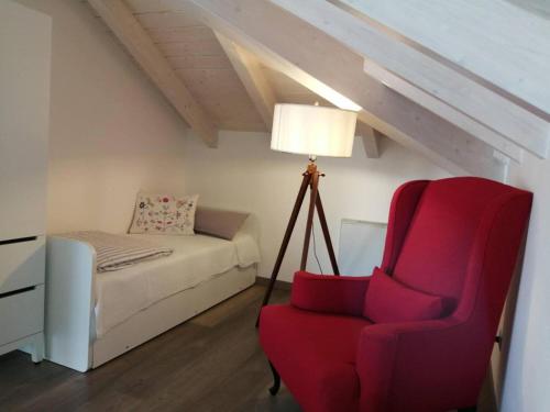 a living room with a red chair and a bed at Bellagio Holiday Home in Bellagio