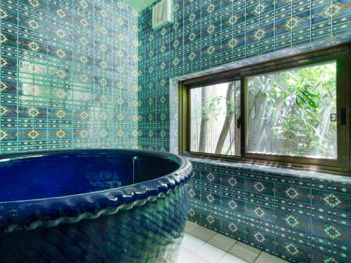 a bathroom with a large blue tub and a window at naokonoza Bettei Umekoji in Kyoto