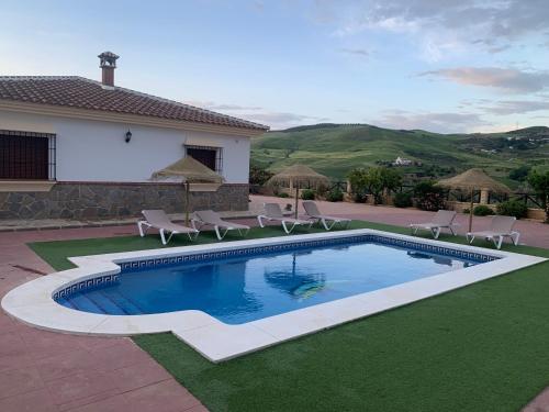 una piscina en un patio con sillas y una casa en El Rincón de Caminito del Rey, en Valle de Abdalajís