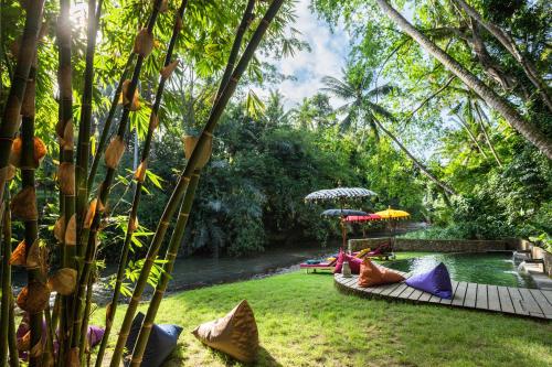 a garden with people laying on the grass with umbrellas at Bamboo Turtles Ecolodge in Ubud