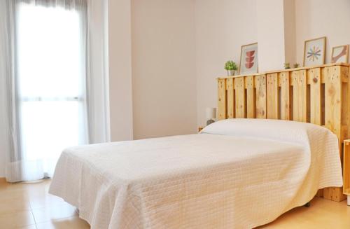 ein Schlafzimmer mit einem Bett mit einer weißen Tagesdecke in der Unterkunft Apartamento Río Salado in Conil de la Frontera