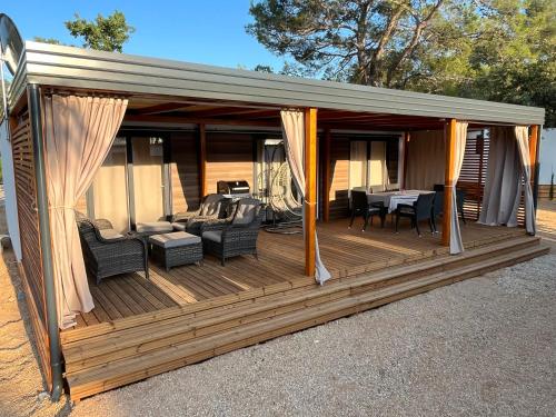 une grande terrasse en bois avec des chaises et une table dans l'établissement Mobile Home Karlo, à Biograd na Moru