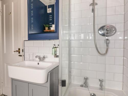 La salle de bains blanche est pourvue d'un lavabo et d'une douche. dans l'établissement 40 Main Street, à Burntisland
