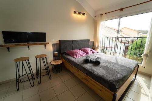 a bedroom with a bed with a television and two stools at Verdon Vacances in Saint-André-les-Alpes