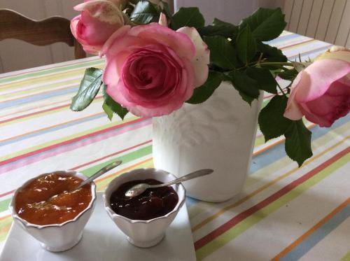 une table avec un vase de roses et deux bols de sauce dans l'établissement Le Clos du Plantis, à Sonnac