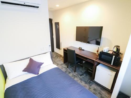新潟市にあるホテルリブマックス新潟駅前のベッドと机、テレビが備わったホテルの部屋