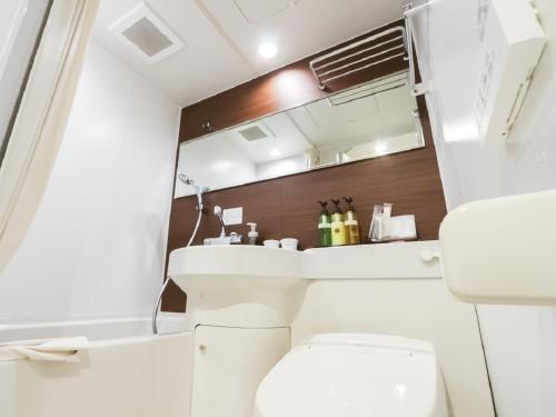 een badkamer met een wit toilet en een wastafel bij HOTEL LiVEMAX Niigata Ekimae in Niigata