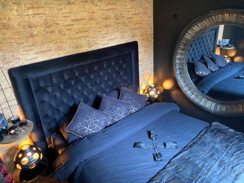 a bedroom with a blue bed and a mirror at La Suite Maléfik in Maing