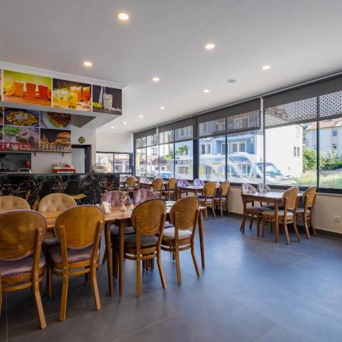 Un restaurante con mesas, sillas y ventanas. en Tanrise City House, en Fethiye