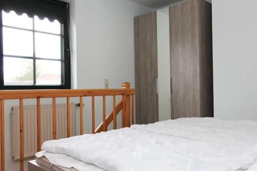 ein Schlafzimmer mit einem weißen Bett und einem Fenster in der Unterkunft Oliver-Grolik in Born