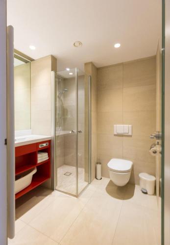 a bathroom with a toilet and a shower at All in Red Thermenhotel in Lutzmannsburg