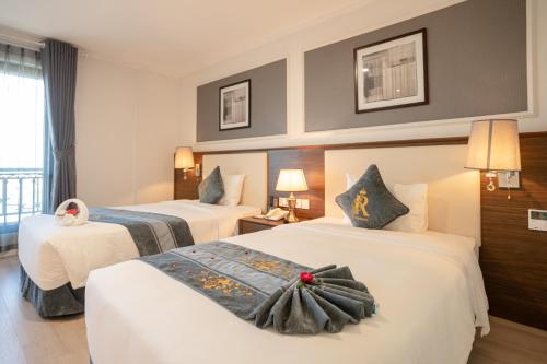 a hotel room with two beds and two lamps at Rex Quang Binh Hotel in Dong Hoi