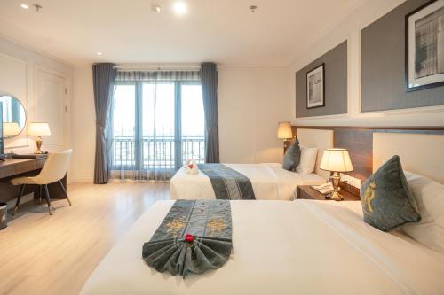 a hotel room with two beds and a desk at Rex Quang Binh Hotel in Dong Hoi