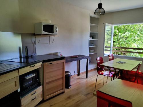 une cuisine avec une table et un four micro-ondes ainsi qu'une salle à manger dans l'établissement L,'ATELIER Impasse Esplanade Michelet, à Rocamadour
