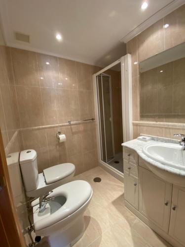 a bathroom with a toilet and a sink and a mirror at Apartamento Marexada Foz in Foz