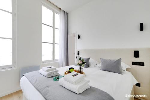 ein weißes Schlafzimmer mit 2 Betten und 2 Fenstern in der Unterkunft CMG - Place des Vosges / Turenne in Paris