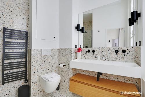 ein Badezimmer mit einem weißen Waschbecken und einem WC in der Unterkunft CMG - Place des Vosges / Turenne in Paris