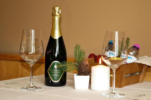a bottle of wine and two glasses on a table at hotel Parco Pineta in Cavareno