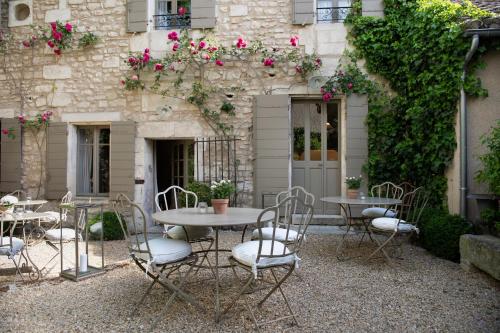 un patio con mesas y sillas frente a un edificio en La Maison du Village en Saint-Rémy-de-Provence