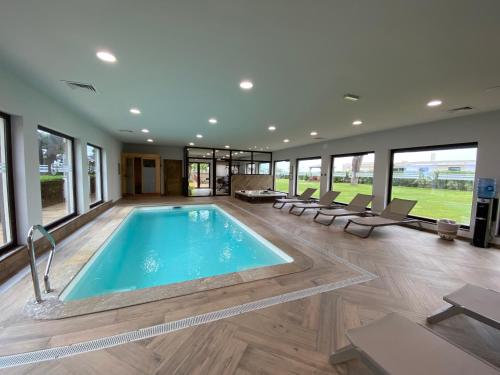 a swimming pool in a large room with windows at Hôtel La Lagune in Lucciana