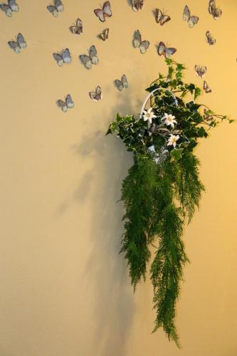 a vase with flowers and butterflies on a wall at hotel Parco Pineta in Cavareno
