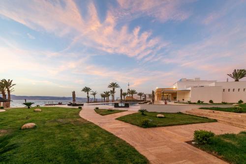 a view of a building and a lawn with palm trees at Luxotel Aqaba Beach Resort & Spa Only 15 years plus in Aqaba