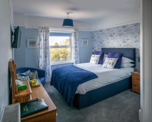 um quarto com uma cama azul e uma janela em Aquila Heights Guest House em Dorchester