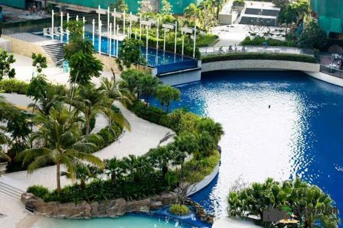 a large pool with palm trees and a bridge at Azure Urban Resort Staycation in Manila