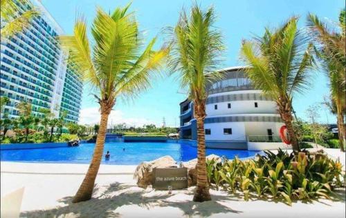 a pool with palm trees in front of a building at Azure Urban Resort Staycation in Manila