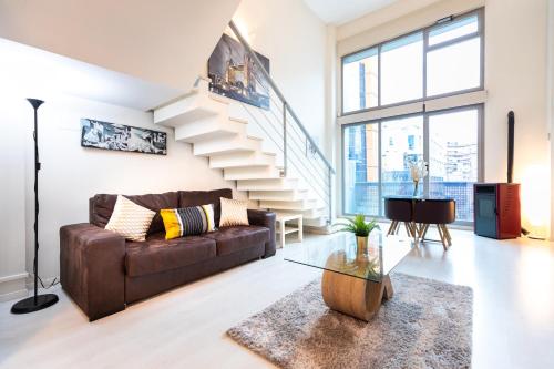 a living room with a couch and a staircase at Oshun Madrid Norte LOFTS & MIDSTAY in Madrid