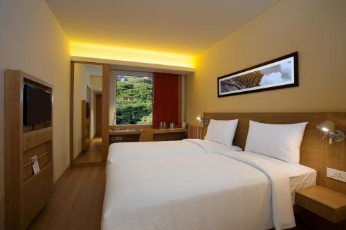 a bedroom with a large white bed and a television at ibis Bengaluru City Centre - An Accor Brand in Bengaluru