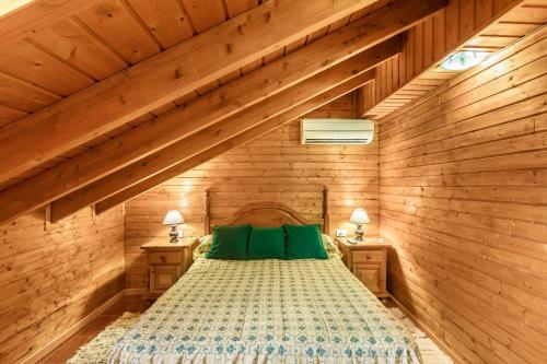 Schlafzimmer mit Holzwänden und einem Bett mit grünen Kissen in der Unterkunft Buhardilla Armonia Rural in Granadilla de Abona