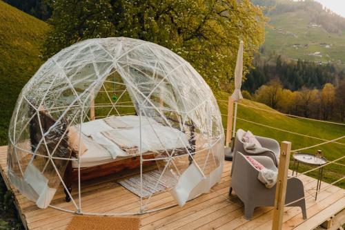 Bett in einem Kuppelzelt auf einer Holzterrasse in der Unterkunft Bubble-Suite in Graubünden in Versam